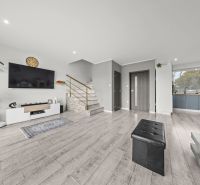 Living room in a family house with wood-patterned flooring, a television, and a staircase.