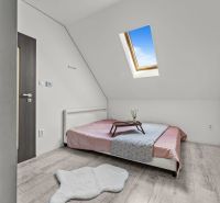 Bedroom in a family house with wood-patterned flooring and a skylight.