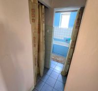 Bathroom in a family house with a blue bathtub and curtains, tiles on the floor.