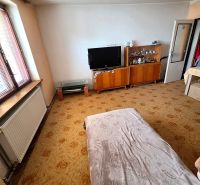 Living room in a family house with a television, display cabinets, and a decorative carpet.