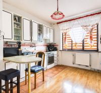 A kitchen in a family house with tiles and a wooden decor floor.