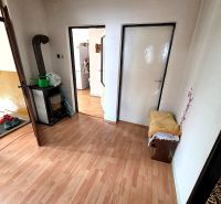 Interior of a family house with a wood-decor floor, a fireplace, and doors to other rooms.
