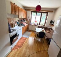 A kitchen with wooden decor, a gas stove, a refrigerator, and a dining table in a family house.
