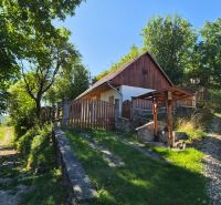 A family house in Mikušovce surrounded by greenery and a path leads to a wooden gate.