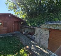 A wooden shelter and a stone building in the garden of a family house in Mikušovce.