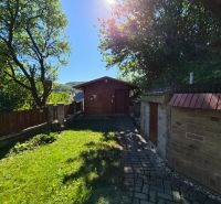 Garden at a family house in Mikušovce, outdoor seating, sunny day, stone pathway.