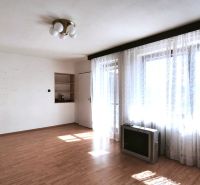 Living room in a family house with a wooden decor floor and large windows with curtains.
