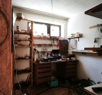Workshop with shelves and a wooden table in a family house, floor with wooden decor.