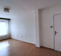 A spacious room in a family house with a wood-decorated floor and a large window.