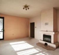 Interior of a family house with a fireplace and large windows with white curtains.