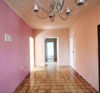 Interior of a family house with a chandelier, pink wall, and tiled floor.