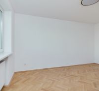 An empty room with a wood-patterned floor in a three-room apartment.