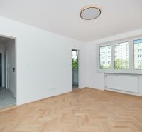 An apartment with a wooden floor design, white walls, and large windows.
