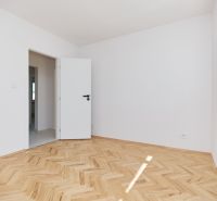 A room with white walls and a wooden decor floor in a 3-room apartment.