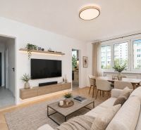 Living room in a three-room apartment with a wooden decor floor and light furniture.