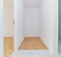 A narrow hallway with white walls in a 3-room apartment and a floor with a wooden decor.