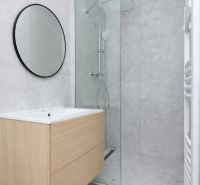 Bathroom in a 3-room apartment with a modern shower and wooden decor on the cabinet.