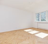 A bright room with white walls and a floor with a wood decor in a 3-room apartment.