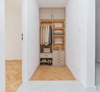 A built-in wardrobe in the hallway of a three-room apartment with a wooden decor floor.
