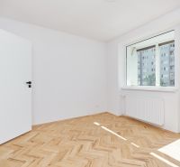 A room in a three-room apartment with a wooden decor floor and a large window.