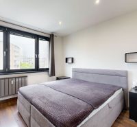 A bedroom in a 4-room apartment with a large window and a floor with a wooden decor.