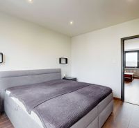 A bright bedroom with a bed and a wooden decor floor in a 4-room apartment.