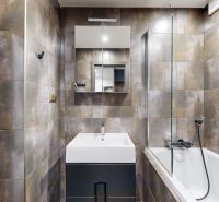 A bathroom in a 4-room apartment with a bathtub, sink, and washing machine in stylish tiles.