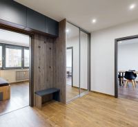 The entrance hall of a 4-room apartment with a wooden decor floor, built-in wardrobe, and coat hooks.