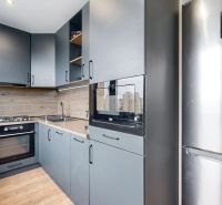A kitchen in a 4-room apartment with modern equipment and a wooden decor floor.