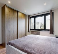 A bedroom in a 4-room apartment with a wooden decor floor, a wardrobe, and a window.