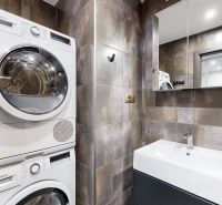 A bathroom with a washing machine, dryer, and sink in a 4-room apartment.
