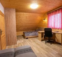 A room in a family house with wooden walls, a floor with a wooden decor, and a work desk.