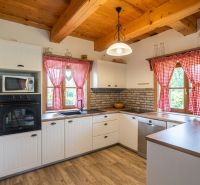 A kitchen in a family house with a brick wall and a wooden decor floor.
