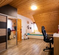 Attic room with wooden ceiling paneling, bed, wardrobe, and floor with wooden decor.