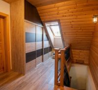 Attic hallway with wooden paneling and wood-decor flooring in a family house.