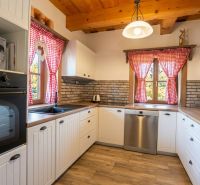 A kitchen unit in a family house with red curtains and a wooden decor floor.