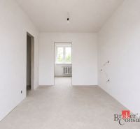 Empty room in a 4-room apartment with white walls and a window.