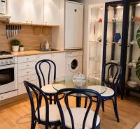 A kitchen in a 2-room apartment with a wooden decor floor and a dining table.