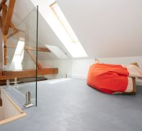 An attic space with glass railings and a colorful bean bag in a three-room apartment.