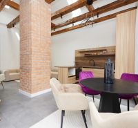 A stylish living room in a three-room apartment with a brick column and wooden beams.