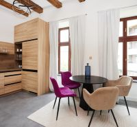 A kitchen corner in a 3-room apartment with colorful chairs and a wooden-patterned floor.