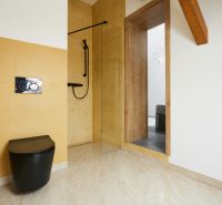 A bathroom with yellow walls, a black toilet, and a shower in a 3-room apartment.