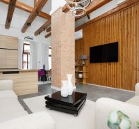 A living room with a brick wall, wooden decor flooring, and comfortable armchairs in a three-room apartment.