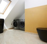 A bathroom with a black toilet, sink, and washing machines in a 3-room apartment.