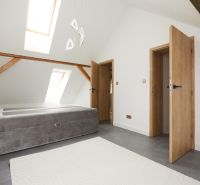 A bright bedroom with a bed, slanted skylights, and wooden elements in a 3-room apartment.