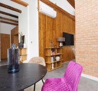 Interior of a 3-room apartment with a brick wall, wooden decor flooring, and colorful furniture.