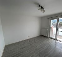 A room with a wooden decor floor and a balcony in a 3-room apartment.