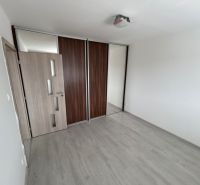 An empty room in a 3-room apartment with a wooden decor floor and a built-in wardrobe.