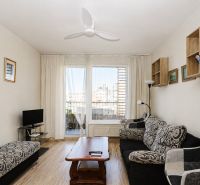 Living room with wood-patterned flooring and patterned furniture in a two-room apartment.