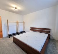 A bedroom with a bed and a hanger in a 2-room apartment, a floor with a wooden decor.